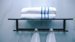 Een badkamer met een marmeren wand, een handdoekhouder met opgevouwen handdoeken, en een handdoekhouder met twee handdoeken.
