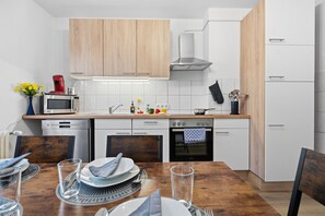 A modern kitchen with wooden cabinets, a microwave, a stove, and a dishwasher. - Central Location – Garage – Balcony – Near University – WiFi (Wuppertal)