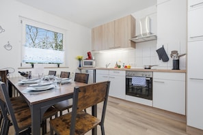 Eine moderne Küche mit weißen Schränken, einem Holzespeiseplatz und einem eingebauten Backofen.