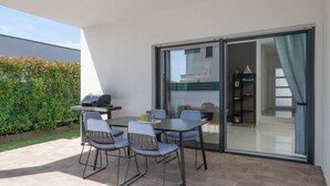 An outdoor patio with a table and chairs, a grill, and a sliding glass door leading to an interior space. - Villa Tony by Villas Guide (Peroj)