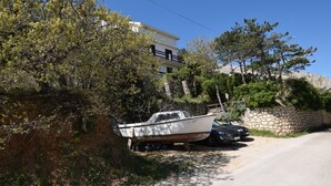 Eine Küstenstraße mit einem abgestellten Boot, einer Steinmauer und einem Gebäude mit einem Balkon.