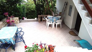 Eine Terrasse mit Tisch und Stühlen, einer Steinmauer und Topfpflanzen.