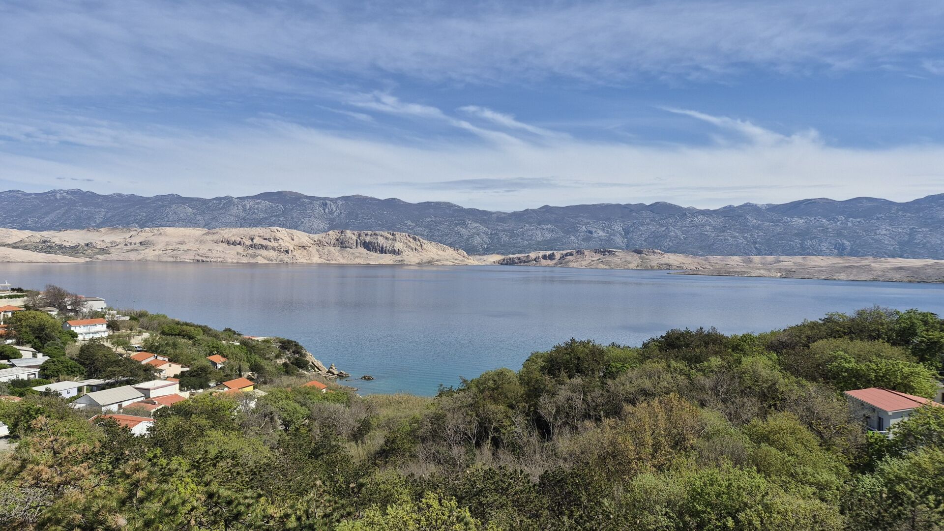 A lake with mountains in the background and a village in the foreground.