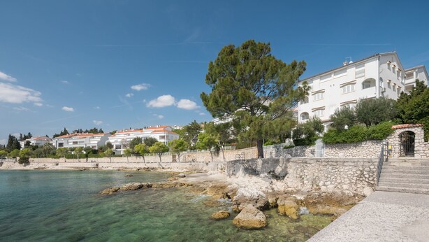 A coastal building with a stone wall, clear water, and a tree. - Apartment Lemon&Soul by Villas Guide (Crikvenica)