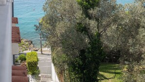 A coastal view with a road leading to a gate, surrounded by dense foliage and a clear blue sea. - Apartment Lemon&Soul by Villas Guide (Crikvenica)