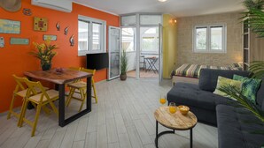 A living room with a sofa, a dining table with chairs, a small round table with a glass, and a TV. - Apartment Lemon&Soul by Villas Guide (Crikvenica)