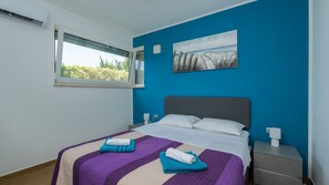 A bedroom with a bed, a window, a painting, and a nightstand. - Villa Sofi by Villas Guide (Peroj)