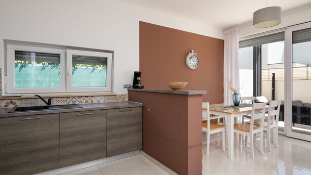 Una cocina moderna con ventana, un reloj y un comedor con sillas y mesa.