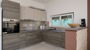 Una cocina moderna con horno Bosch, salpicadero con diseño y ventana con vistas.