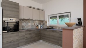 A modern kitchen with a Bosch oven, patterned backsplash, and a window with a view. - Villa Sofi by Villas Guide (Peroj)