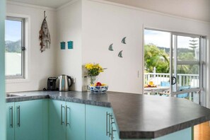 Une cuisine avec des armoires de couleur turquoise, une machine à café et un vase rempli de fleurs.
