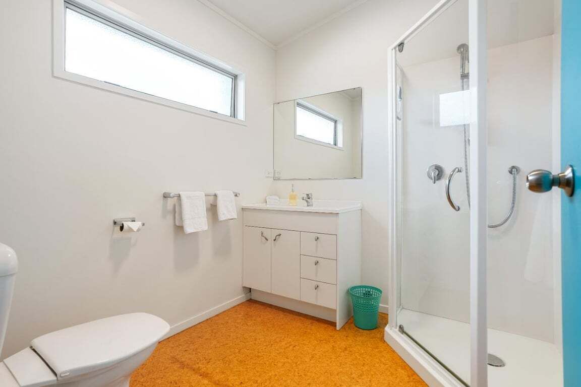 Une salle de bain comprenant des toilettes, un lavabo, un miroir, une douche et une fenêtre.