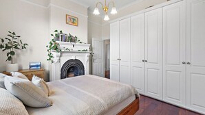 A bedroom with a bed, a fireplace, a large wardrobe, and a hanging light fixture.