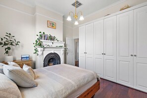 Ein Schlafzimmer mit Bett, Kamin, großem Kleiderschrank und einer Pendelleuchte.