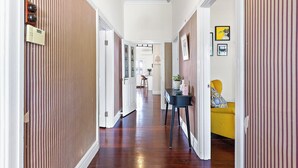 A hallway with striped walls, a wooden floor, and a yellow sofa in the distance.