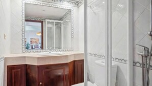 Un baño con un espejo grande, un lavabo, armarios de madera y una zona de ducha.