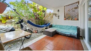 Un patio con una hamaca, una motocicleta, una mesa y un sofá.