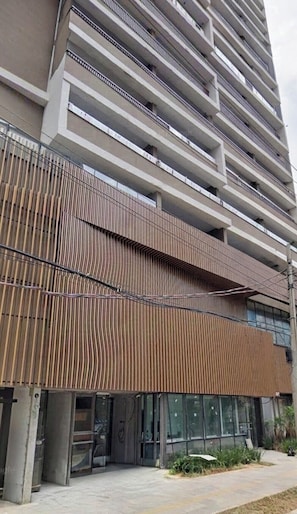 Un edificio de varios pisos con diseño moderno, que cuenta con balcones y una fachada con listones verticales de madera.
