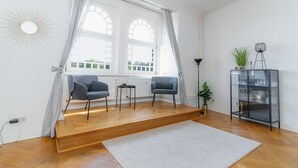 A living room with two chairs, a small table, a glass cabinet with dishes, a potted plant, and a large window with curtains. - fewo1846 - Strandkoje / luxurious old apartment for max 5 persons with sea view (Flensburg)