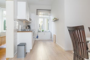 A modern kitchen with white cabinetry, a wooden floor, and a window with a view. - fewo1846 - Strandkoje / luxurious old apartment for max 5 persons with sea view (Flensburg)