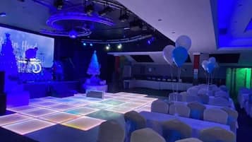 A conference room with a stage, chairs, and a large screen.