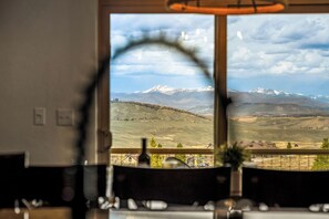 Blick durch ein Fenster auf eine Berglandschaft, einschließlich schneebedeckter Gipfel.
