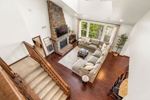 Ein geräumiges Wohnzimmer mit Kamin, einer Couch und einer Treppe.