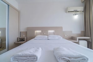 A hotel room with a bed, two bedside tables, an air conditioning unit, and a mirror. - Muup Resort Çeşme (Cesme)