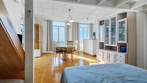 Een slaapkamer met een bed, een bureau met stoel, een kledingkast en uitzicht door een raam.