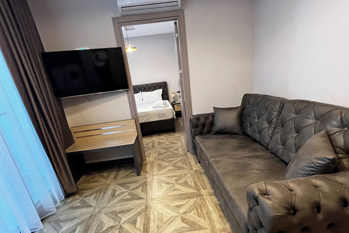 Una habitación con cama, sofá, aire acondicionado y suelo estampado.
