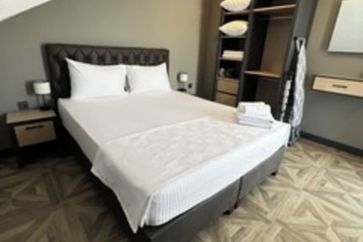 A hotel room with a large bed, a nightstand, a wardrobe, and a mirror.