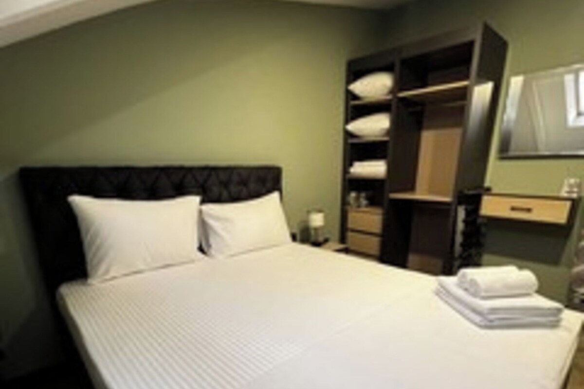 A neatly made bed with pillows, a bedside table with a lamp, and a built-in wardrobe with shelves.