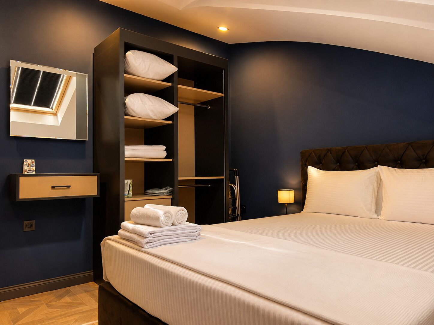 Une chambre d’hôtel comprenant un lit, une armoire intégrée, un miroir et une table de chevet.