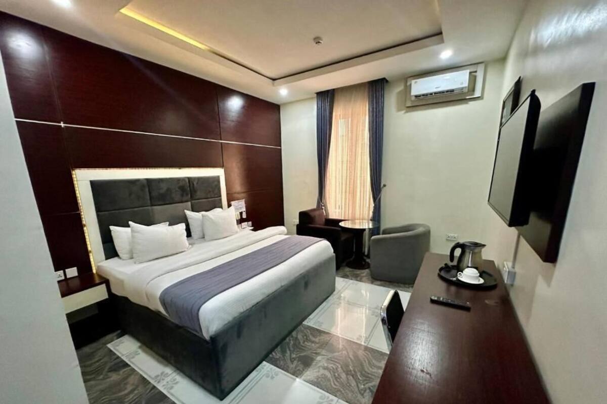 Habitación de hotel con una cama grande, un escritorio, una silla, un televisor y un aire acondicionado.