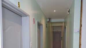 A hallway with marble flooring, doors, and a ceiling light.