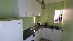 A compact kitchen with a washing machine, a microwave, and a sink.