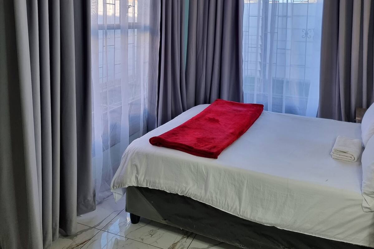 Ein Hotelzimmer mit Bett, Vorhängen und Blick aus dem Fenster.