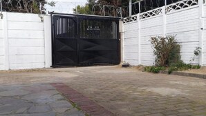 A gated area with a paved walkway, a white fence, and a black gate.
