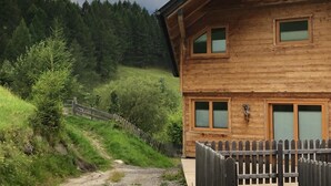 Une cabane en bois, entourée d’une clôture en bois, et un sentier qui y mène.