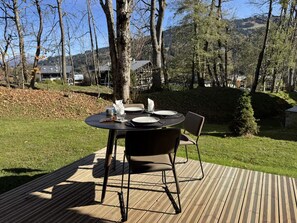Ein Essbereich im Freien mit einem runden Tisch, Stühlen und Blick auf die umliegende Landschaft.