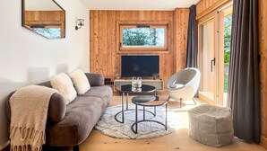 A modern living room with a sofa, a round coffee table, a TV, and a chair. - K1 facing the slopes ski in / ski out Megève (Megève)