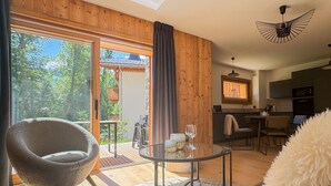 A modern living room with a glass table, a fluffy white sofa, and a view of a wooden deck and outdoor furniture. - K1 facing the slopes ski in / ski out Megève (Megève)