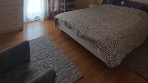 Ein Schlafzimmer mit Bett, Schreibtisch, Stuhl, Fernseher und Klimaanlage.