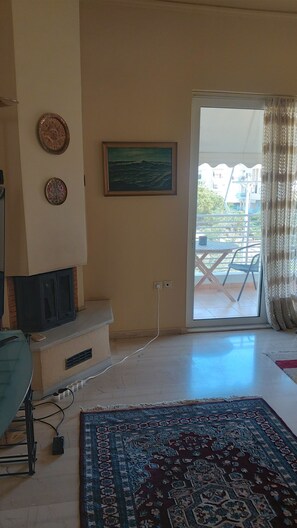 A living room with a flat-screen TV, a patterned rug, and a painting on the wall. - 2-bedroom apartment in fabulous Glyfada (Glifada)
