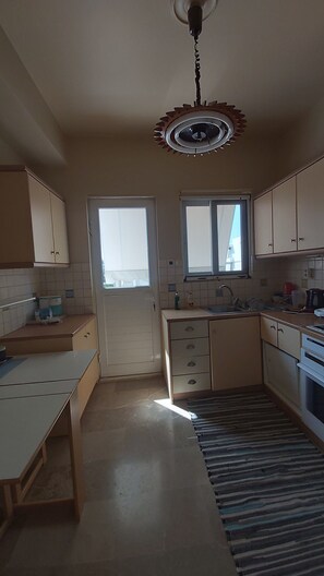 A kitchen with cabinets, a stove, a sink, and a window. - 2-bedroom apartment in fabulous Glyfada (Glifada)