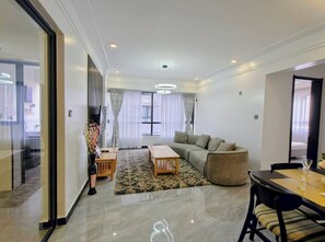 Ein modernes Wohnzimmer mit Sofa, Couchtisch, Esstisch mit Stühlen und einer Glastrennwand.