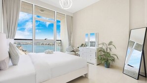 Une chambre à coucher avec un grand lit, une commode, un miroir et une plante en pot.