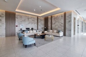 A spacious lobby with a marble wall, a sofa, a coffee table, and a round side table. - FIRST CLASS |1BR| Sea View Paradise | Scenic Views (Ras Al Khaimah)