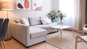 Ett modernt vardagsrum med en soffa, ett soffbord och en lampa. På väggen hänger abstrakta tavlor och på bordet står en växt.