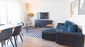 A modern living room with a sofa, a TV, a dining table with chairs, and a patterned rug. - White and black by Prater #40 (Vienna)